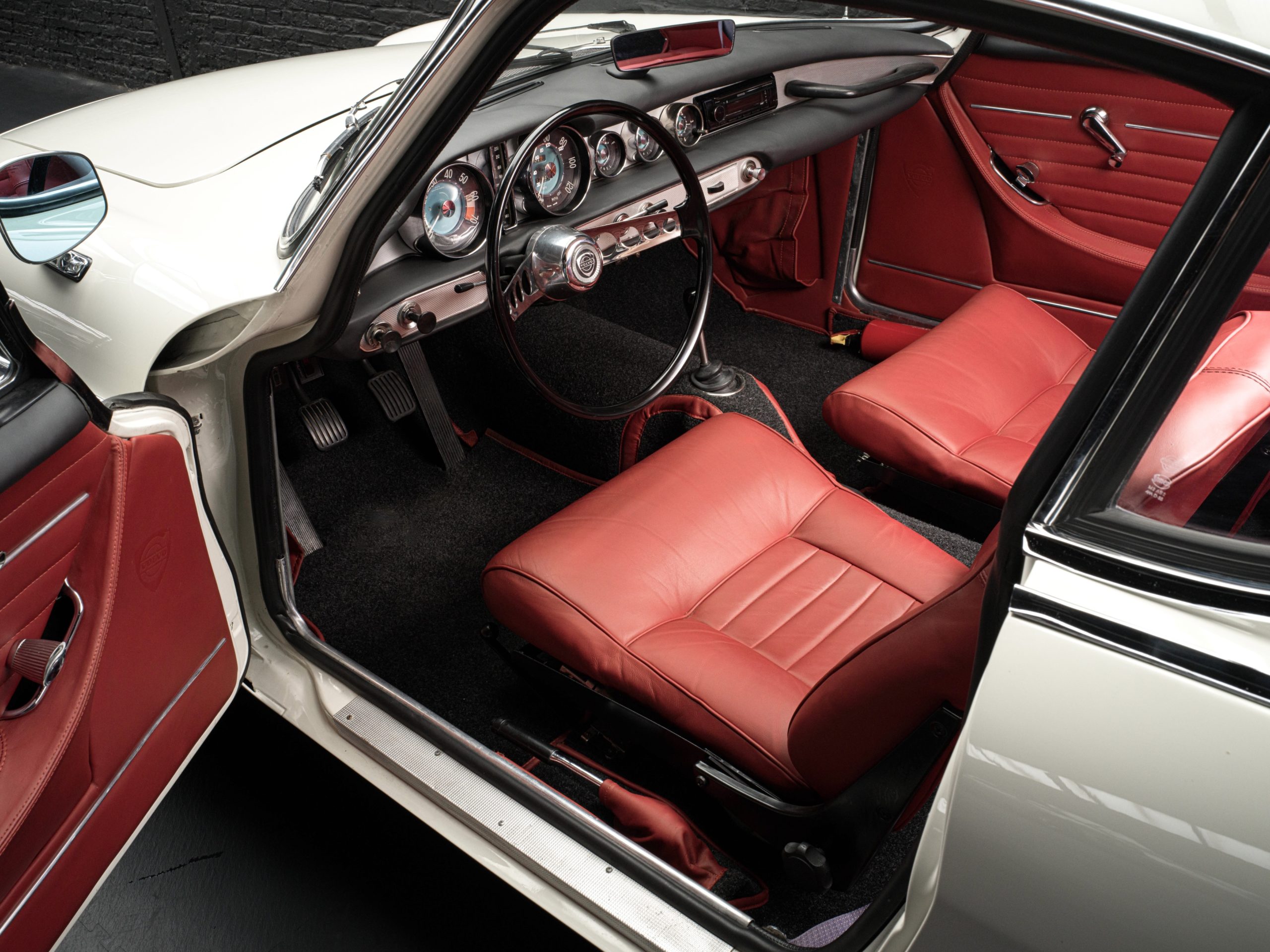 vue intéreure d'une Volvo 1800S de 1965 blanc cassé intérieur rouge en vente chez Classic 42